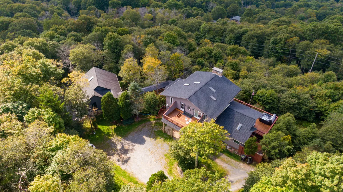 This inviting exterior shows the home's deck overlooking a forested landscape, perfect for morning coffee, evening stargazing, or simply taking in the sunset after a day on the slopes or trails. The deck acts as a transition space between adventure-filled days and cozy relaxation.