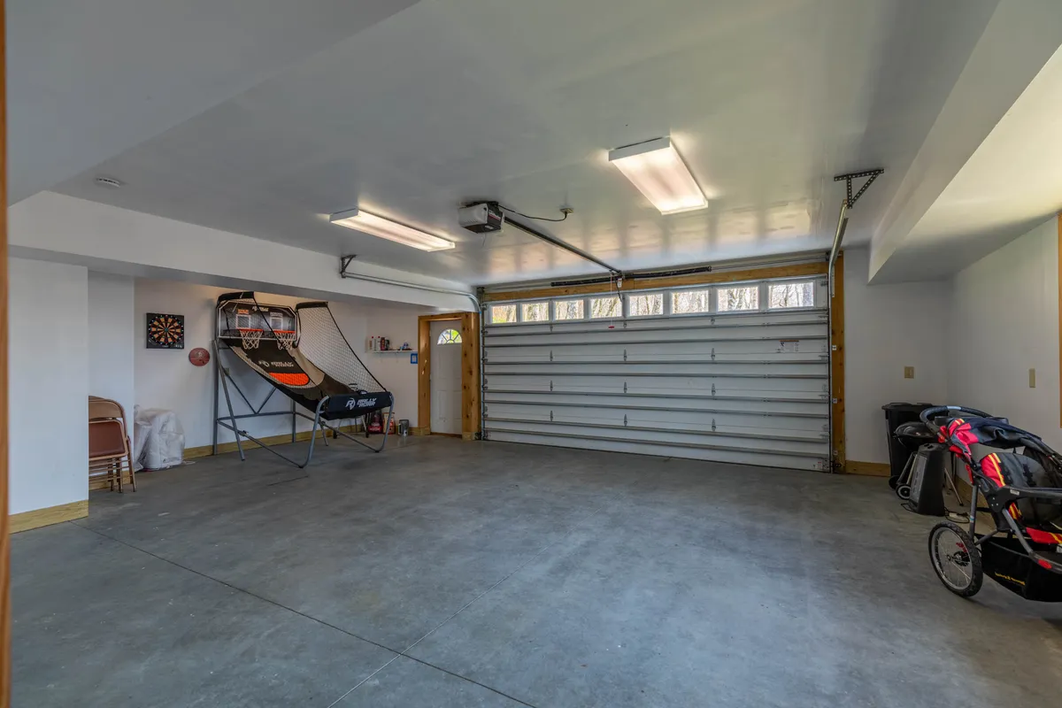 An inviting garage interior features a basketball shooting game, dartboard, and storage for sports equipment. The garage door hints at the elevated living space above, reinforcing the Chalet’s multi-level layout and family-friendly amenities.